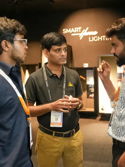 An animated discussion among three attendees in front of a smart lighting display. The expo sparks conversations that lead to new ideas and collaborations.