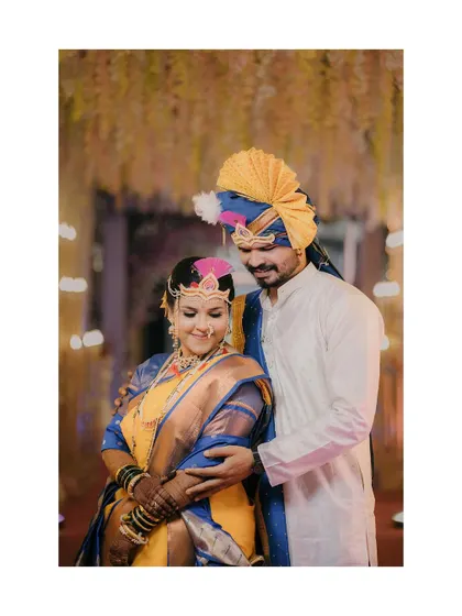 The groom lovingly embraces his bride during their Maharashtrian lagn. Her traditional mundavalya and his pheta are key elements of their beautiful wedding look.