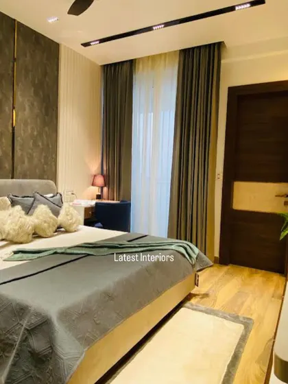 This shot captures the overall ambiance of the bedroom, with its wooden flooring, dark curtains, and carefully placed lighting. The room feels like a cozy and luxurious cocoon.