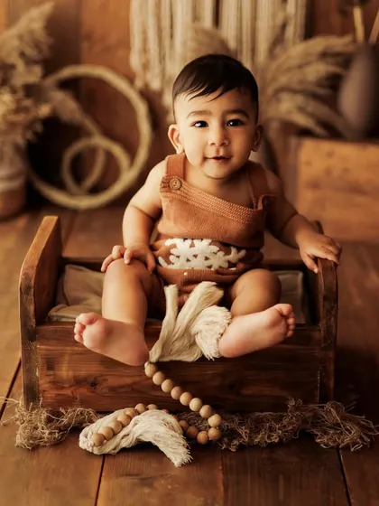 A sweet and curious look from a baby boy during his sitter session. The wooden beads and natural textures add to the charm of this portrait.
