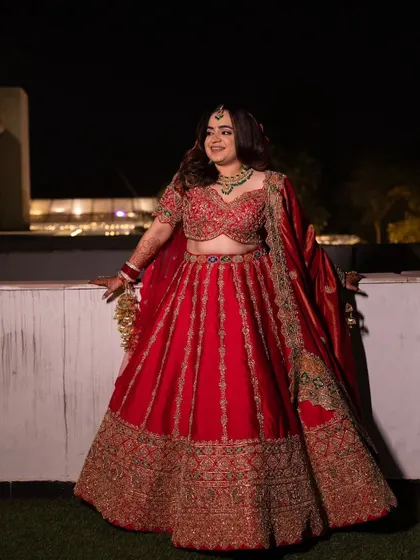 A full view of this regal red lehenga. The rich color and intricate gold embroidery make for a timeless bridal look that is both grand and elegant.