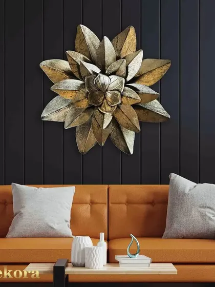 A single, large metal flower with layered petals in a burnished gold finish. This piece is ideal for adding a bold, singular statement to a wall.
