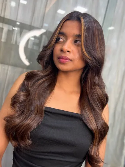 A side view of the warm caramel face-framing highlights, showing how they blend seamlessly with the natural base color.