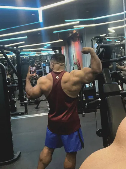 A back double bicep pose in the gym mirror.