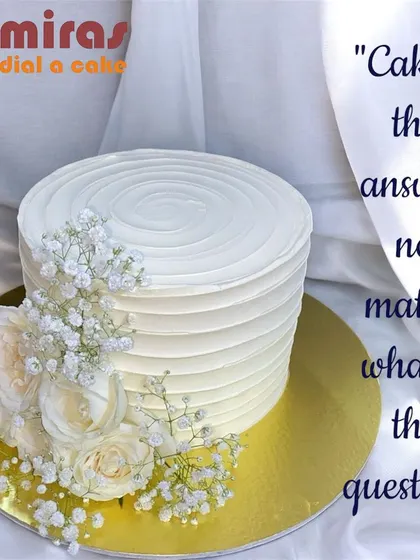 A minimalist masterpiece. This white buttercream cake with a textured finish is elegantly decorated with fresh baby's breath and white roses, proving that simplicity is the ultimate sophistication.
