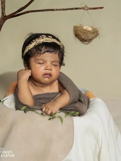 A rustic and natural theme for this sleeping newborn. Wrapped in earthy tones and nestled beside a tiny bird's nest, this setup creates a serene, storybook feel.