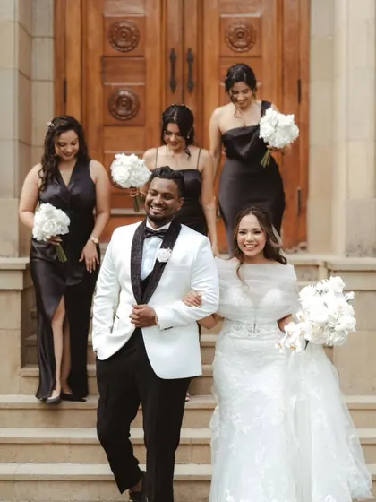 The bride and groom walking down the steps of the church with their bridesmaids. A classic and elegant shot capturing the joy of the wedding party.