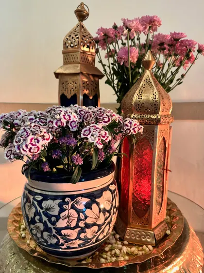 A beautiful centerpiece featuring traditional Turkish lanterns, a blue and white ceramic pot, and fresh flowers, celebrating the vibrant culture.