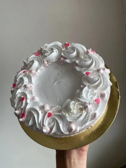 A simple white mini cake with piped swirls and pink heart sprinkles. Sometimes less is more.