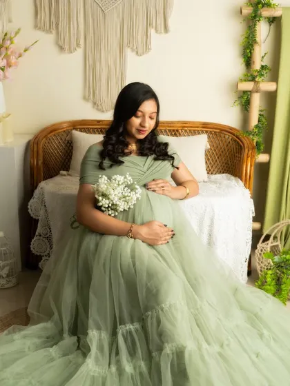A quiet, contemplative moment. This seated portrait in a green gown is perfect for capturing the emotional side of pregnancy.