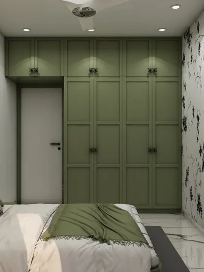 The room's storage solution is a floor-to-ceiling wardrobe in a matching shade of green, featuring classic paneling and hardware.