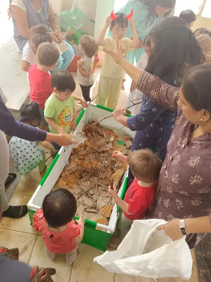 Children add dry leaves and twigs to our compost bin, learning about decomposition and creating nutrient-rich soil.