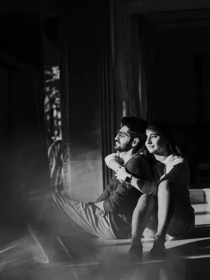 A black and white photo capturing a couple in a quiet moment, with beautiful light creating a soft, reflective flare. This artistic shot showcases our use of natural light to create mood and emotion.