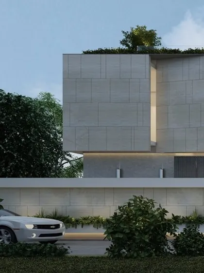 'The Courtyard House' in Shimoga features a monolithic facade of light grey stone tiles. The clean, minimalist form is punctuated by a single slit window, creating a sense of privacy and intrigue from the street.