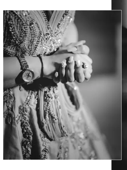 A close-up, artistic black and white shot focusing on the bride's hands, showing her engagement ring and detailed manicure. We believe in capturing the small, significant details.