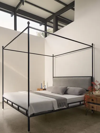 The four-poster bed in a Pavilion House bedroom adds a touch of classic elegance to the modern, minimalist space. The high ceilings and large windows ensure the room feels airy and connected to the outdoors.