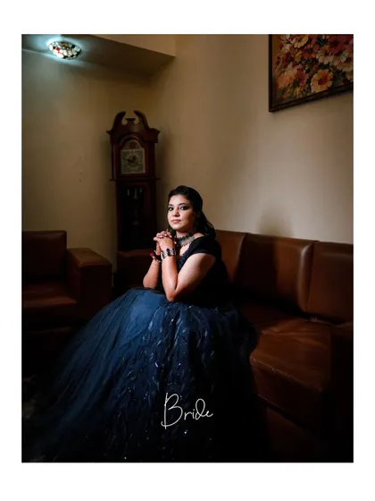 A poised and elegant portrait of the bride in a stunning blue gown for one of her pre-wedding events, captured in a classic indoor setting.