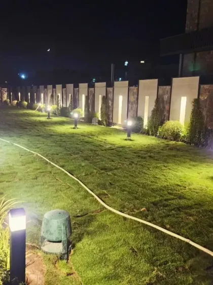 The final result of the lawn renovation. A perfectly green, manicured lawn complemented by modern lighting along the boundary wall, creating a high-end, resort-like feel for this large property.