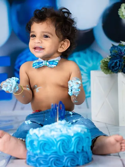 A smile that can light up the whole room. Even covered in cake, his happiness shines through in this first birthday portrait.