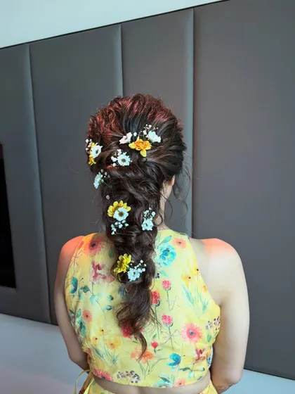 A close-up of the messy braid with yellow and white flowers, a perfect hairstyle for a vibrant Haldi or Mehendi ceremony.