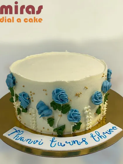 A simple and elegant buttercream cake with delicate blue roses piped along the side. This design shows that beauty can be found in simplicity, perfect for any occasion.