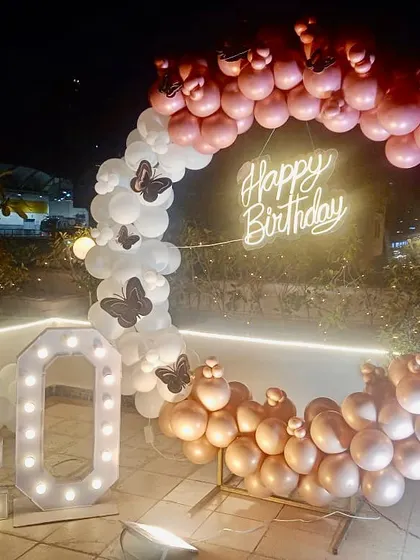 A 40th birthday celebration on a terrace. The circular balloon arch and marquee numbers create a beautiful focal point against the evening sky.