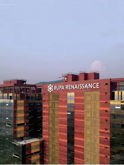 A closer view of the Rupa Renaissance rooftop and facade, showing the branding and the building's signature color scheme. The design considers climate and sun incidence to create a comfortable and self-sustainable working environment.