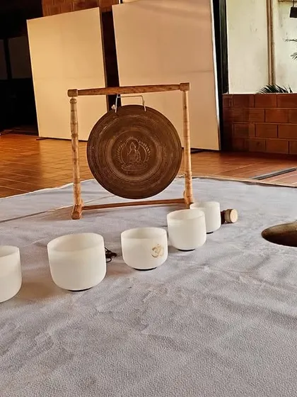 A close-up of the setup for a sound meditation session. You can see the arrangement of crystal singing bowls, a chau gong, and a wave drum, each ready to contribute its unique frequency to the healing experience.
