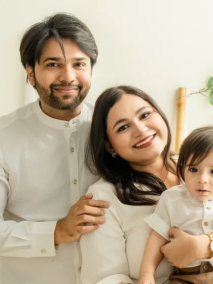 A classic family portrait where everyone is connected. The soft smiles and gentle hold create an image of unity and love, beautifully framed by the natural studio decor.