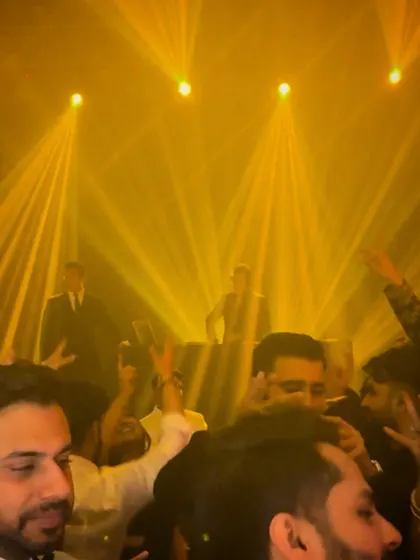 Another angle of the crowd under the golden lights, showing guests with their hands in the air. It's a testament to a night where the music truly takes over.