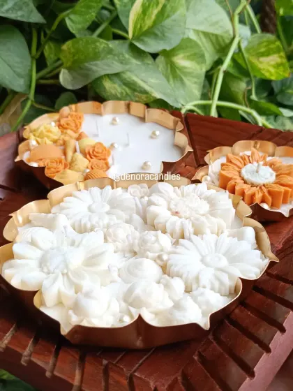 I offer urli candles in a variety of sizes and designs. Here you can see a large all-white floral urli, a smaller sunflower design, and a seashell-themed piece, showcasing the range of styles available.