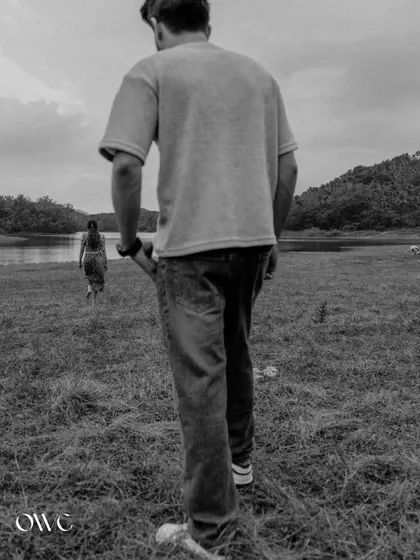 An artistic black and white photo with the groom in the foreground and the bride walking away, creating a sense of narrative and perspective.