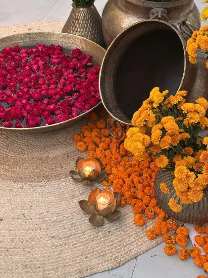 A detail shot of brass urlis with floating rose petals and marigolds, placed on jute mats for a rustic, earthy feel.