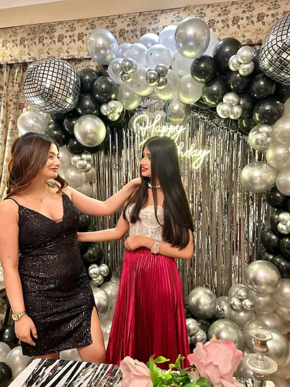 The birthday girl and her friend posing in front of the black and silver balloon arch we created for her special day.