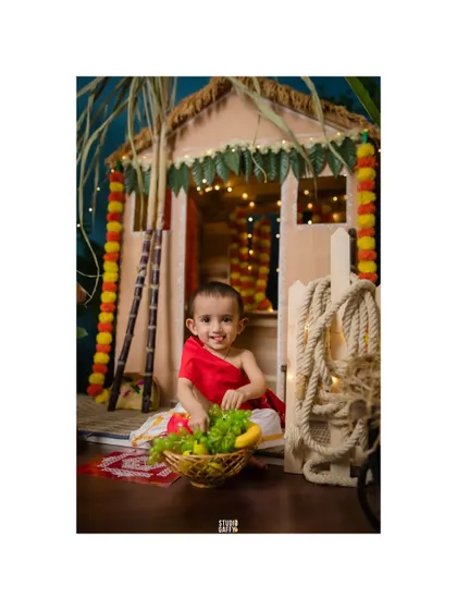 A sweet baby with a basket of fruit in our festive Pongal hut.