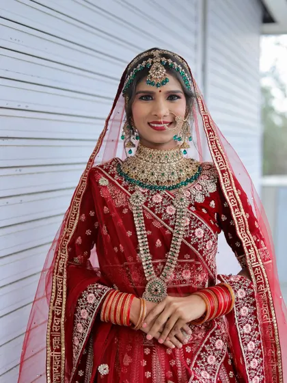 A full-length view of the bride in her red lehenga. The entire look, from the draping of the dupatta to the makeup, was done by a student during our portfolio shoot.