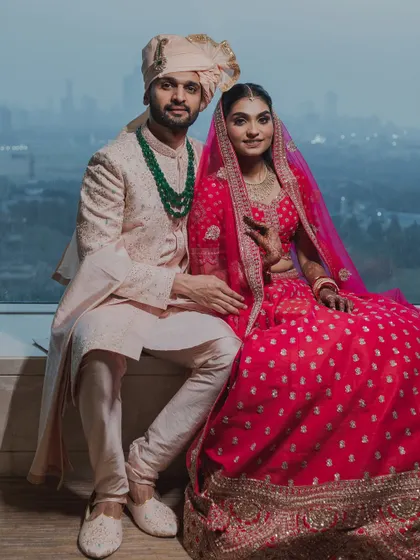 A classic seated portrait of the bride and groom against a city skyline. A modern and elegant wedding photograph.