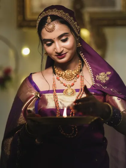 A candid moment of the bride during a ritual. The warm lighting highlights her glowing skin and the beautiful details of her makeup.