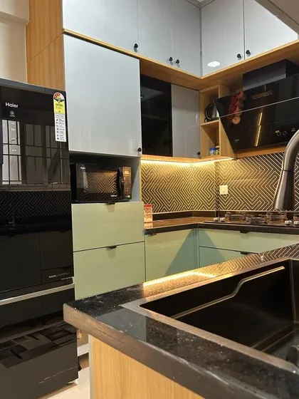 This view highlights the smart storage solutions, including a dedicated unit for the microwave and refrigerator. The handleless cabinets contribute to the kitchen's clean and modern aesthetic.