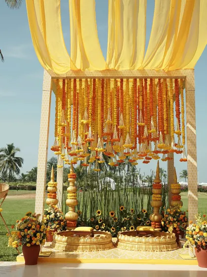 The Haldi seating setup in Goa, with a canopy of marigolds and traditional brass urlis, all set against a lush green lawn.