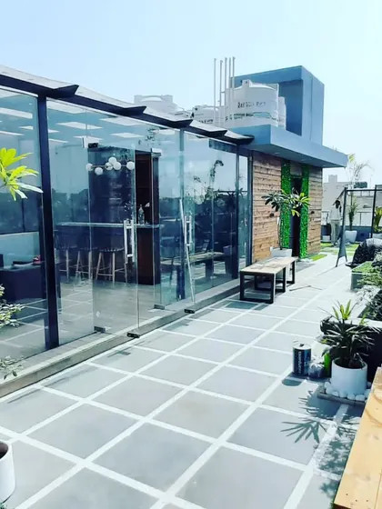 This project showcases a glass room with an extended tiled patio area, surrounded by planters. It demonstrates how we can landscape the entire terrace for a complete, cohesive design.