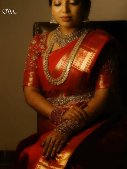 A regal portrait of the bride seated, showcasing her magnificent saree and jewellery.