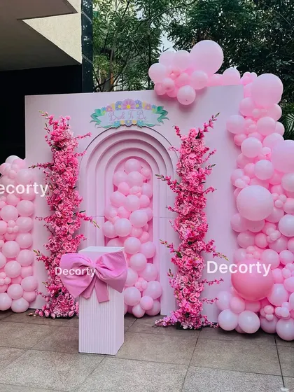 An elegant and monochromatic 'Pop of Pink' birthday backdrop. This design uses various shades of pink balloons and stunning pink floral arrangements for a chic and sophisticated look.