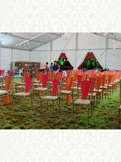 Guest seating inside a tent, with chairs decorated with vibrant pink and orange drapes. This simple touch adds a splash of color and ties the seating into the overall theme.