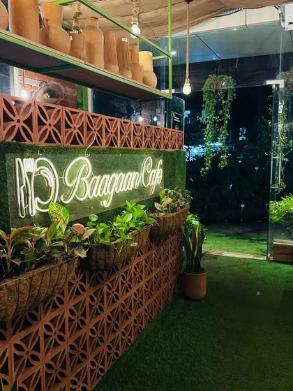 The entrance to our cafe at night, with the neon sign glowing against the terracotta brick wall and lush planters. It’s the first hint of the green world that awaits you inside.