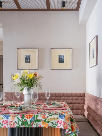 The dining nook in the 'Modern Muse' project, featuring a custom-built bench with pink channel-tufted upholstery. The space is set for a meal, showcasing its functionality and charm.