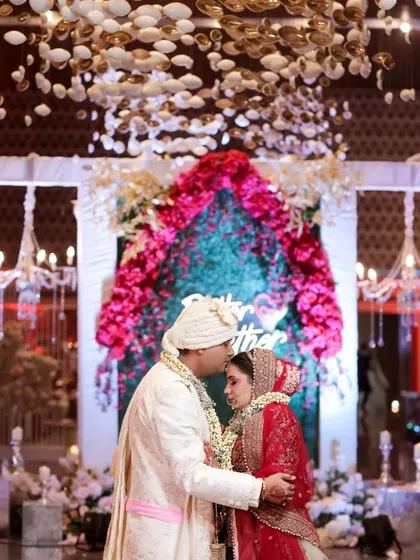 A tender moment during the wedding ceremony. The groom kisses the bride's forehead under a beautiful ceiling installation, a gesture of love and respect.