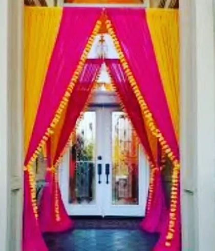 A doorway decorated with bright pink and yellow drapes, creating a festive and welcoming entrance.