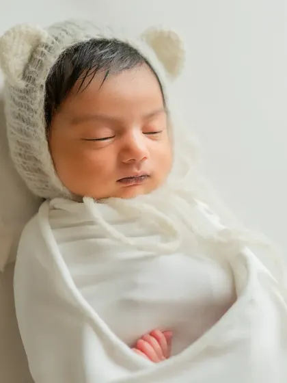 A serene close-up focusing on the baby's peaceful face and the soft texture of the bear bonnet.