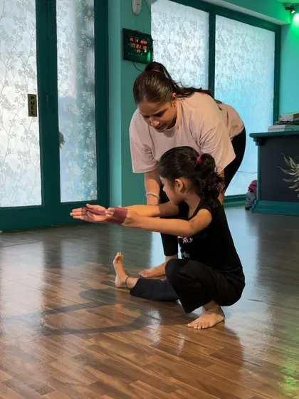 Guiding a student into a proper squat, ensuring her knees are aligned and her back is straight.